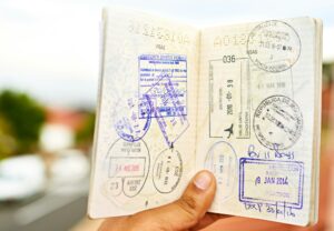 Shot of an unidentifiable young man holding open a passport full of visa stamps